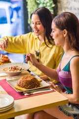 Latinx female friends together eating happy in a Ecuadorian food restaurant. Traditional meal