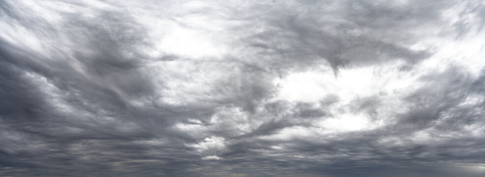 Panorama of gray cloud filled rain sky with local transparent areas
