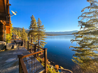 a gorgeous winter landscape at Lake Tahoe with blue lake water, lush green trees and plants and...