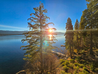 a gorgeous winter landscape at Lake Tahoe with blue lake water, lush green trees and plants and...