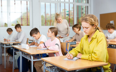 Young boys and girls studying in classroom during lesson in school.