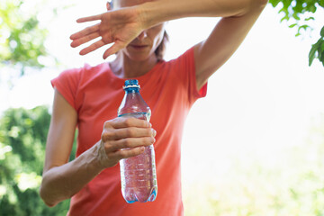 young woman drinking water in the heat of the day, cooling off from summer heat wave 