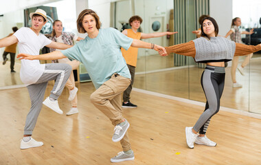 Teenager girls and boys performing jive dance in ballroom.