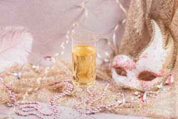 Masquerade ball holiday background. Glass of white champagne, Venetian carnival mask and feathers...