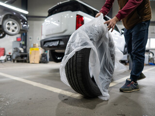 Mechanic unpacking new tires in a garage.  © Михаил Решетников