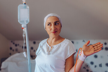 A patient with cancer poses confidently with an IV in hand, showcasing a cheerful and spirited...
