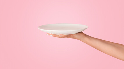 Millennial woman holding empty plate on pink background, mockup for your design