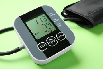 Blood pressure measuring device on green background, closeup