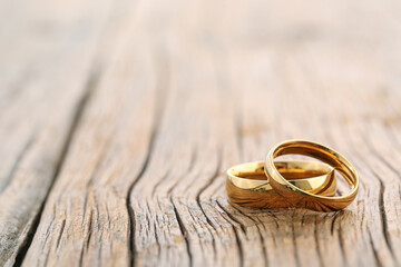 Beautiful golden wedding rings on wooden background, space for text