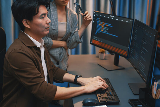 IT developers discussing with point to intelligent website development coder system running data online two screens information technology at neon light room at modern office. Infobahn.
