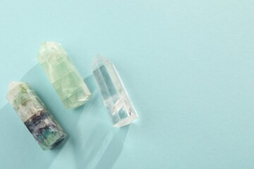 Beautiful natural gemstones on light blue background, flat lay. Space for text