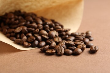 Paper coffee filter and beans on brown background, closeup