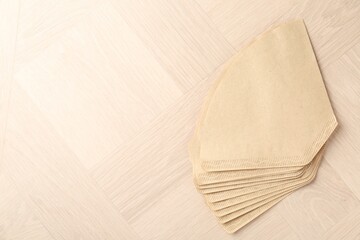 Paper coffee filters on light wooden table, top view. Space for text