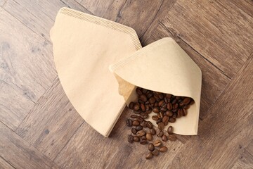 Paper filters and coffee beans on wooden table, top view