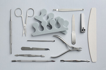 Set of pedicure tools on light grey background, flat lay