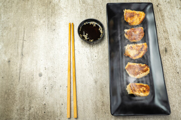 Fried chinese dim sum dumpling, gyoza, jiaozi or mandu in the plate with chopsticks and soy sauce...