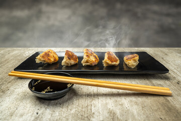 Fried chinese dim sum dumpling, gyoza, jiaozi or mandu in the plate with chopsticks and soy sauce...