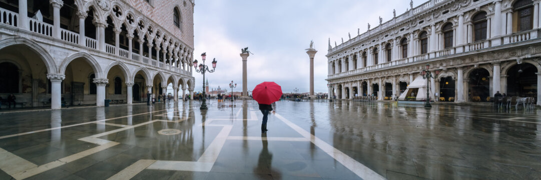 Woman with umbrella standing at St Mark's square flooded at high tide, Venice, Italy
