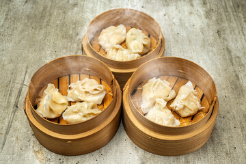 Assorted chinese dim sum dumpling on bamboo wooden basket bowl on wooden table