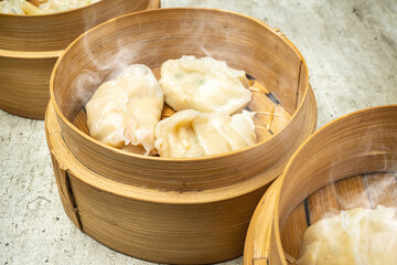 Assorted chinese dim sum dumpling on bamboo wooden basket bowl on wooden table