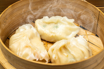 Chinese dim sum dumpling on bamboo wooden basket bowl on wooden table