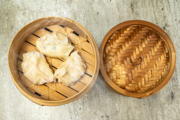 Chinese dim sum dumpling on bamboo wooden basket bowl on wooden table