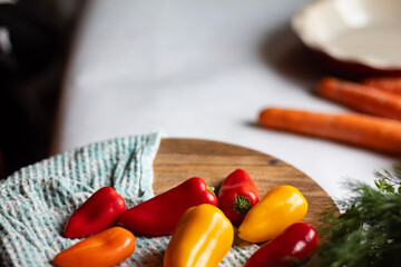 Fresh peppers lie on a wooden cutting board.