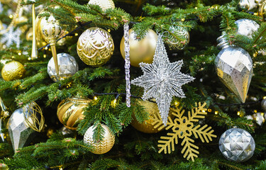 Christmas tree with golden and silver ornaments on blurred background.