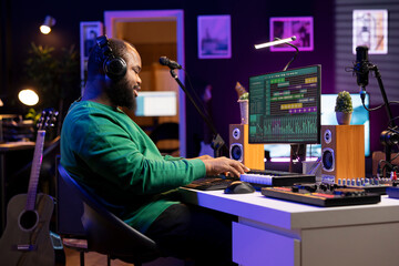Sound designer playing piano and recording audio files on DAW software, producing new tracks and...