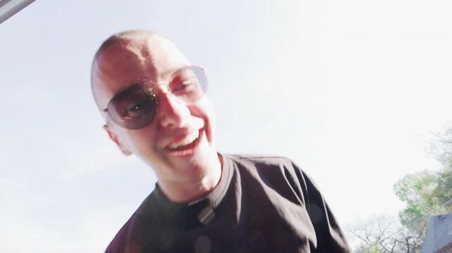 wide-angle shot of a young man showing off a snake tattoo on top of his head.