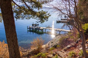 a gorgeous winter landscape at Lake Tahoe with blue lake water, lush green trees and plants,...