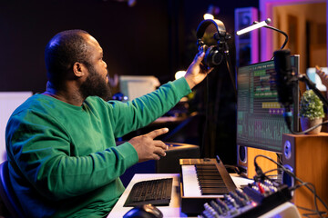 Audio technician works with recording tools in his home studio, using mixing console and pre amp...
