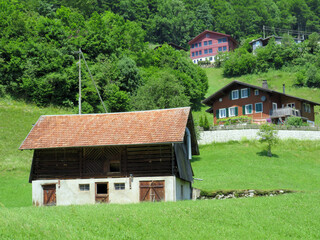 Fototapeta premium Traditional rural architecture and family livestock farms on the shores of Lake Lungern - Canton of Obwald, Switzerland (Traditionelle Architektur am Ufer des Lungernsees - Schweiz)