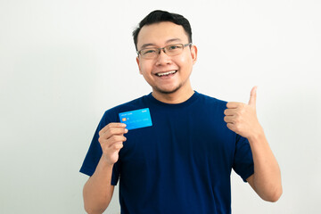 Happy asian man hold credit card with thumb up pose. Banking, Financial isolated, blue color concept.