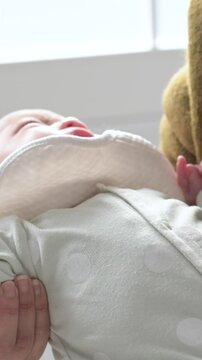 泣く日本人の赤ちゃんを抱っこしてあやす親 子育てや育児のライフルタイル縦動画　泣き止まずに困る悩む育児イメージ 
