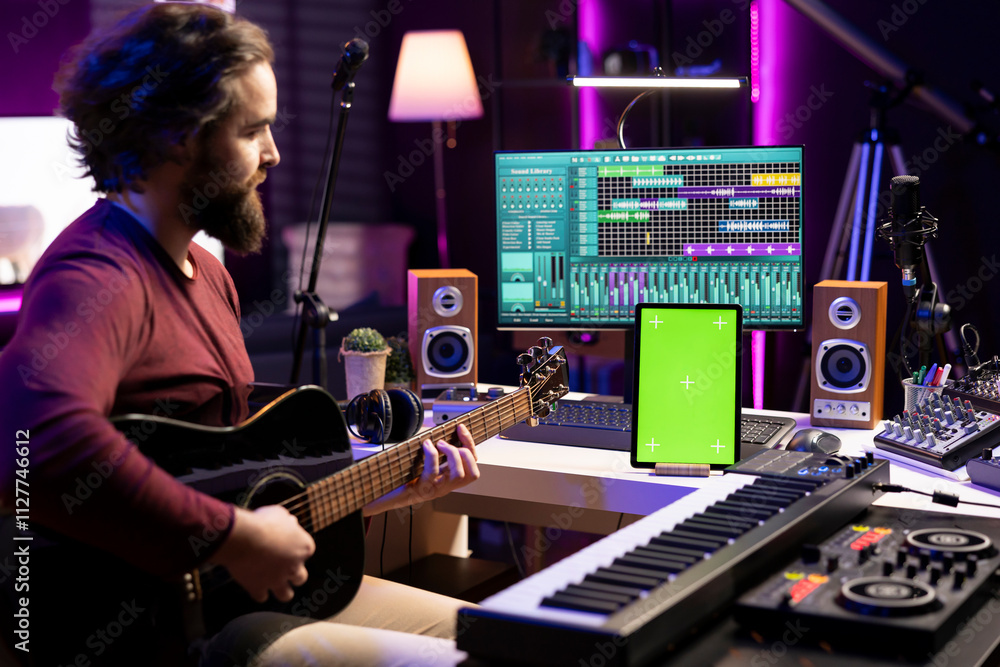 Aufkleber Composer playing acoustic guitar after following online tutorial, learning new strings accords in his home studio. Music producer learning to p lay a new melody on instrument, greenscreen layout.