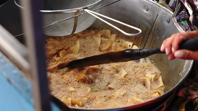 Close up wood stick stiring potato in oil bath street food Mexico