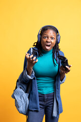 Angry gamer raging and screaming after receiving game over screen, holding controller. Irked african american woman yelling after losing videogame, playing with gamepad, studio background