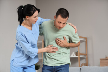 Female doctor helping man with heart attack at home