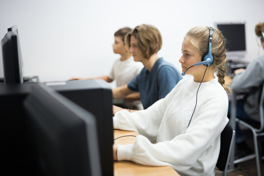 Schoolgirl in headphones working with computers in classroom - Powered by Adobe