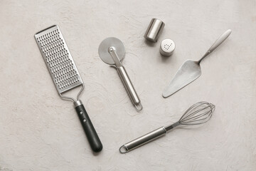 Set of kitchen utensils with stainless steel pizza cutter and spices on light background