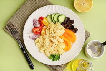 Plate with delicious Italian pasta salad on green background