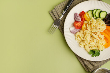 Plate with delicious Italian pasta salad on green background with space for text