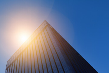 A building with a bright sun shining through the sky. A skyscraper glares at the sun. Tall building with blue sky and blue sun. Tall building with blue sky and sun glares at the lifestyle skyscrapers.