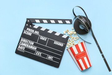 Movie clapper with popcorn and film reels on blue background