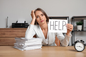 Tired businesswoman holding paper with word HELP in office. Deadline concept