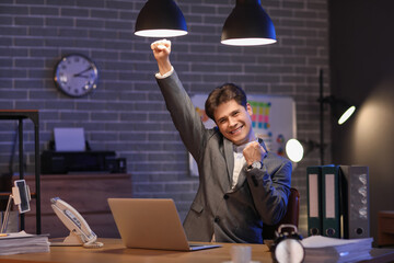 Happy businessman meeting deadline in office at night
