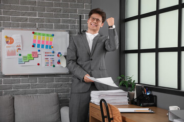 Happy businessman with papers meeting deadline in office