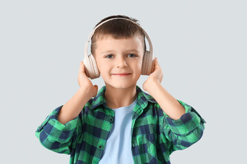 Cute little boy in headphones on light background, closeup