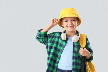 Cute little boy with backpack on light background